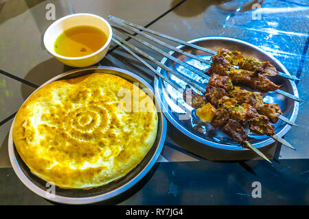 Traditionnelle ouïgoure épicé chaud les brochettes d'agneau au cumin tasse de thé et du pain naan Banque D'Images