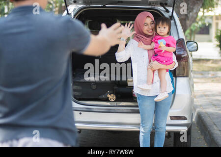 Jeune famille musulmane , transports, loisirs, road trip et personnes concept - happy woman and little girl waving au père de dire au revoir et bienvenue besid Banque D'Images