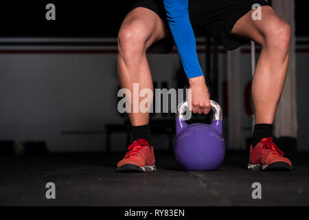 Jeune homme athlétique de récolte en sportswear prêt à lever grand sport dans kettlebell Banque D'Images