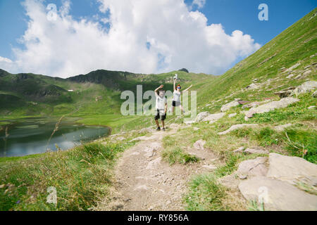 Jeune couple qui saute dans une grande vallée avec le lac glaciaire sur l'arrière-plan, en Ordesa, Huesca, concept de la liberté Banque D'Images