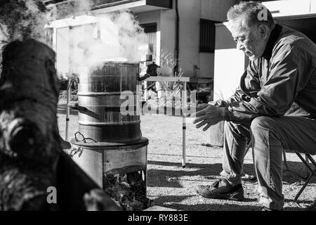 Un ancien homme d'Asie de se réchauffer par le feu de camp Banque D'Images