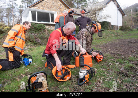 Compétences en foresterie l'éducation : les personnes prenant part à un atelier de formation d'une journée à l'entretien et en toute sécurité l'utilisation d'une scie. Pays de Galles UK Banque D'Images