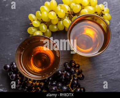 Photo le haut de deux verres de jus, noir et vert grappes de raisin Banque D'Images