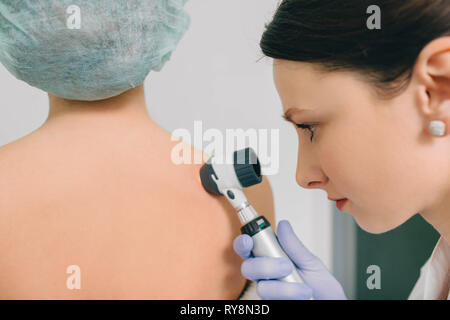 Dermatologue examine les taches sur la peau du patient avec un dermatoscope. L'examen de la peau dermatologie, mole Banque D'Images