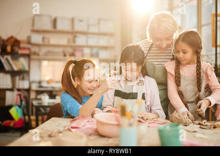 Portrait de femme professeur d'art qui travaillent avec peu de filles dans la classe de poterie, scène éclairé par la lumière du soleil serein, copy space Banque D'Images