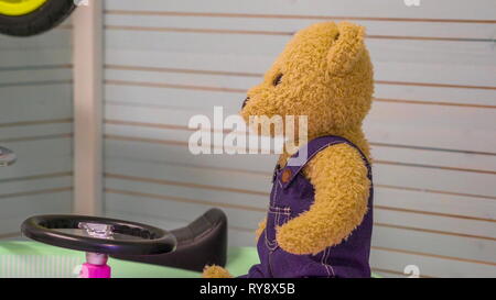 Un ours en peluche brun équestre sur la petite voiture à l'intérieur du jouet pour enfants Prix de la chambre Banque D'Images