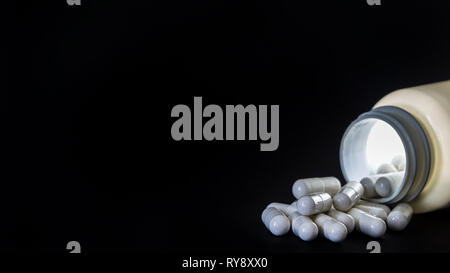 Une boîte de pilules magiques. Un blanc éclatant de comprimés renversé sur fond noir. Copie vierge de l'espace pour propre texte. Banque D'Images