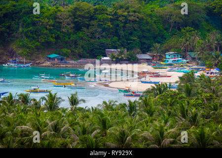 Belle plage Village in Tropical Cove, avec des bateaux d'excursion et de palmiers, Diapila - Palawan - Philippines Banque D'Images