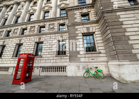 Scène londonienne, téléphone rouge fort et vert lime électrique vélo E location de vélos à l'extérieur du gouvernement de gauche d'immeuble de bureaux à Whitehall, Londres, UK Banque D'Images