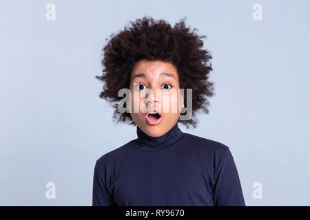 Dark-haired curly petit enfant d'être choqués et ouvrir la bouche Banque D'Images