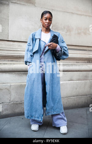 LONDON - 17 février 2019 : les participants à l'extérieur rassemblement élégant 180 The Strand pour la Semaine de la mode de Londres. Jeune fille dans un manteau en denim bleu avec une fente sur le b Banque D'Images