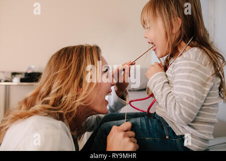 Femme médecin examinant la gorge de petite fille avec la spatule. Pédiatre contrôle la gorge d'une petite fille. Banque D'Images