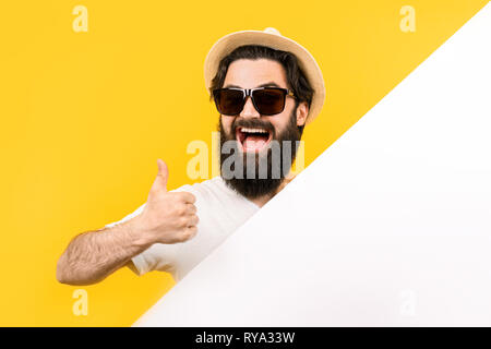 Studio portrait d'un barbu à lunettes de soleil et chapeau, un homme tient une bannière blanche et affiche un panneau d'été, comme Banque D'Images