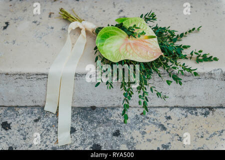 Le bouquet de mariée. Beau bouquet de fleurs et de verdure, décoré de ruban de soie longue se trouve sur un fond texturé Blanc Banque D'Images