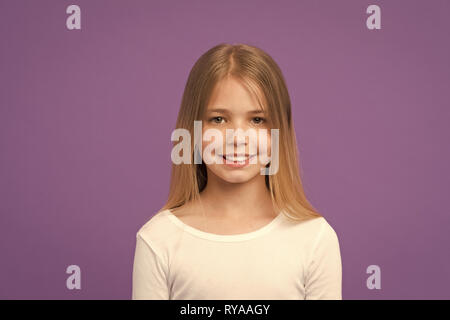 Fille avec beau sourire isolé sur fond violet. Avec l'enfant mignon visage studio portrait. Modèle avec cheveux blonds brillant et les yeux verts. Kid en Wh Banque D'Images