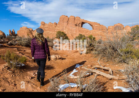 Femme marche sur le sentier Skyline arch avec un peu de neige fondante sur le terrain Banque D'Images