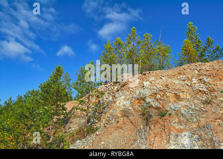 Barre rocheuse recouverte de pins contre le ciel bleu. Banque D'Images