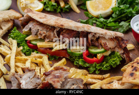 Les gyroscopes, shawarma, Plats à emporter, de l'alimentation de rue. Sandwich avec la viande sur la table en bois, vue rapprochée Banque D'Images
