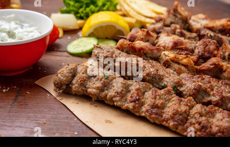 Kebab, turc, grec traditionnel sur table en bois de la viande, les pommes de terre et sauce tzatziki Banque D'Images