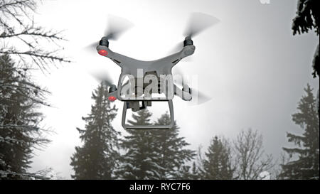 La photo en gros plan d'un drone en vol stationnaire. L'UAV de l'antenne est représentée dans un environnement neigeux de l'hiver, en face de certains arbres alpins couverts de neige. Banque D'Images