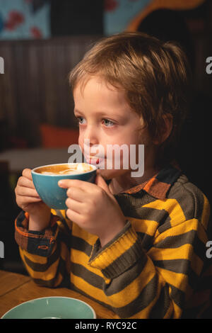 Un agréable automne portrait d'un beau petit garçon. Un petit garçon de 5 ans boit du cacao. De l'automne. L'hiver. Banque D'Images