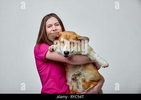 Belle fille avec un Welsh Corgi sur ses mains sur un fond gris, copy space Banque D'Images