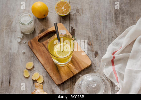 Tasse de thé au gingembre avec du citron. Tasse de thé au gingembre avec du citron. Mug en verre vert de thé chaud sur la table en bois. Citrons en tranches sur une planche à découper Banque D'Images