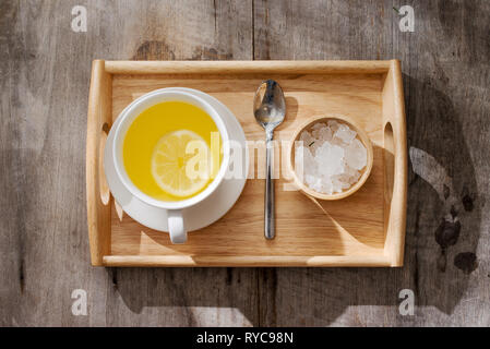 Tasse de thé au gingembre avec du citron. Tasse de thé au gingembre avec du citron. Mug en verre vert de thé chaud sur la table en bois. Citrons en tranches sur une planche à découper Banque D'Images