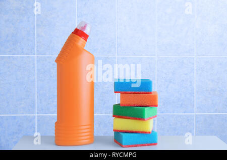 Bouteille de détergent et une éponge en mousse sur un plateau blanc. Arrière-plan de carreaux bleus. Banque D'Images