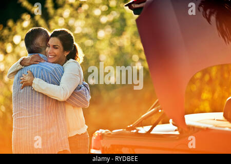 Mature couple hugging à côté de leur voiture. Banque D'Images