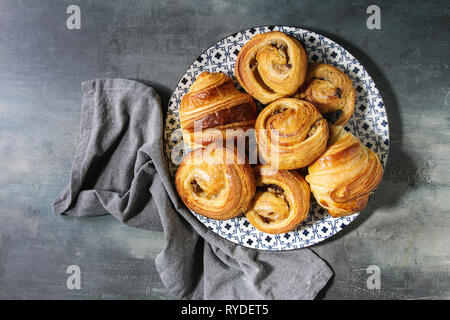 Variété de pâte feuilletée faite maison à la cannelle brioches et croissants servis dans une plaque en céramique bleu sur fond de texture. Mise à plat, de l'espace Banque D'Images