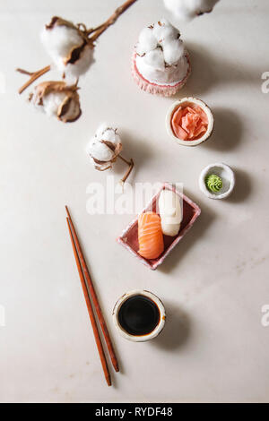 Set à Sushi nigiri de saumon et en rose butterfish plat de service en céramique, baguettes, bols de sauce soja et gingembre mariné, fleurs de coton plus whi Banque D'Images