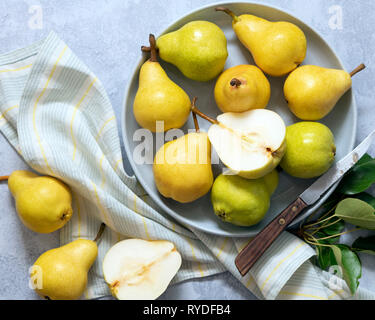 Jaune et vert de poires dans un bol avec une poire coupées en moitiés. Banque D'Images