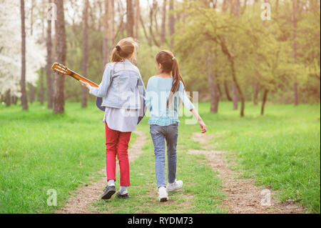 Deux professionnels de jeunes filles avec guitare chant de marche le long de la chanson sentier du parc vert printemps Banque D'Images