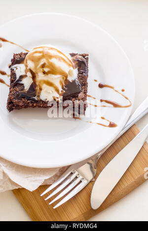 Brownie au chocolat avec une boule de crème glacée à la vanille sauce chocolat mod sur une plaque blanche Banque D'Images