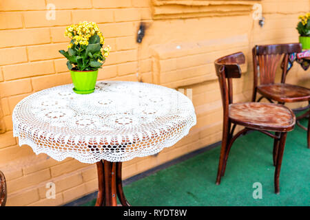 Table en bois vides à l'extérieur restaurant café avec des chaises sur le trottoir et la rue aux fleurs en pot de plante en pot avec personne dans l'été Banque D'Images