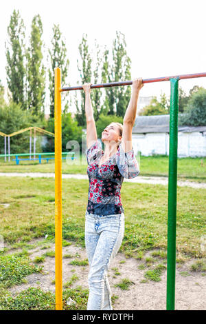 Jeune femme d'ajustement à la jeune fille en train de faire tirer sur la barre de l'onduleur dans Green Park en Ukraine Banque D'Images