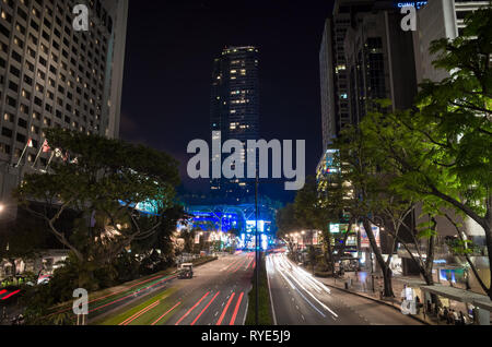 Une exposition longue, les phares de voitures sur Scotts Road, avec les gratte-ciel de Singapour Banque D'Images