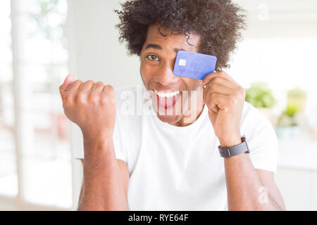 African American man holding credit card crier fier et célébrer la victoire et le succès très excité, encourageant l'émotion Banque D'Images