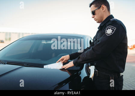 Policier en uniforme écrit une amende sur route Banque D'Images