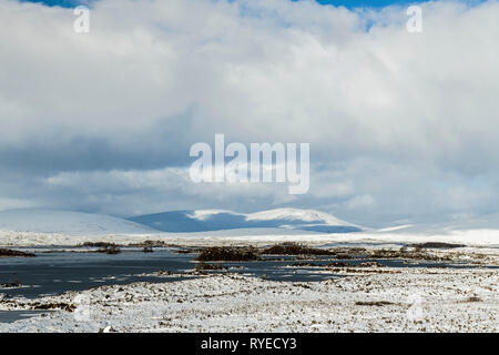 Rannoch Moor dans les Highlands écossais sous la neige en février. La photo montre des montagnes enneigées avec des ombres de nuages sur eux. Banque D'Images