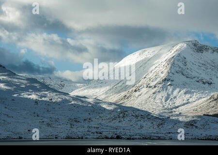 Rannoch Moor dans les Highlands écossais sous la neige en février. La photo montre des montagnes enneigées avec des ombres de nuages sur eux. Banque D'Images