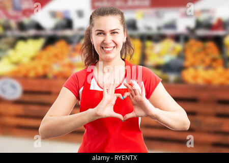 Smiling supermarché ou hypermarché employée comme symbole coeur doigts de retenue pour l'amour concept Banque D'Images