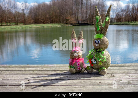 La figure de paille Bunnys sur le môle-gang plank avec sky réflexion sur l'eau à un lac à Pâques et printemps concept d'arrière-plan Banque D'Images