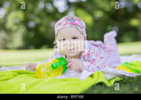 Smiling baby girl avec bouteille d'eau dans parc d'été Banque D'Images