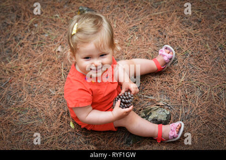 Little girl holding a cône dans le bois forêt Banque D'Images