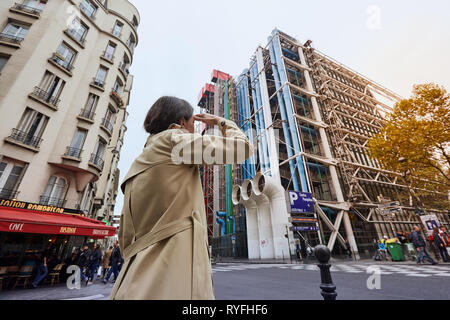 Jeune fille dans une veste jaune en face du Centre Pompidou à Paris Banque D'Images