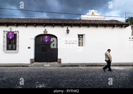 Antigua, Guatemala - 23 mars 2018 : Les hommes de passer par une maison de style colonial 'Casa de las Golondrinas' avec des cloudcape Banque D'Images