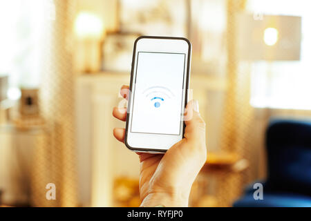 Gros plan sur smartphone Avec signal wifi faible dans la main de femme moderne dans le salon. Banque D'Images