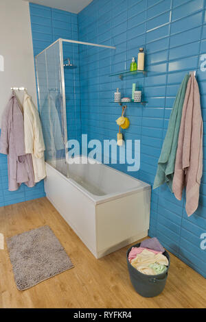 Salle de bains moderne avec baignoire, douche blanc, panier à linge et carreaux bleu Banque D'Images